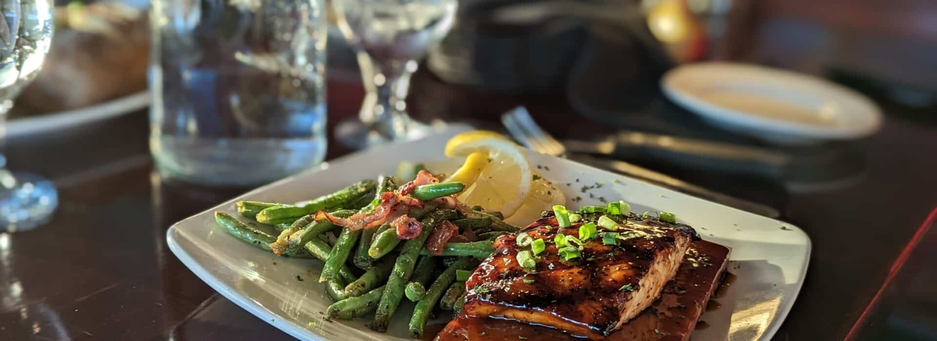 “Cedar plank salmon glazed with a rich sauce, served with sautéed green beans and lemon wedges at a restaurant near Spencer House Bed & Breakfast in Erie, PA.