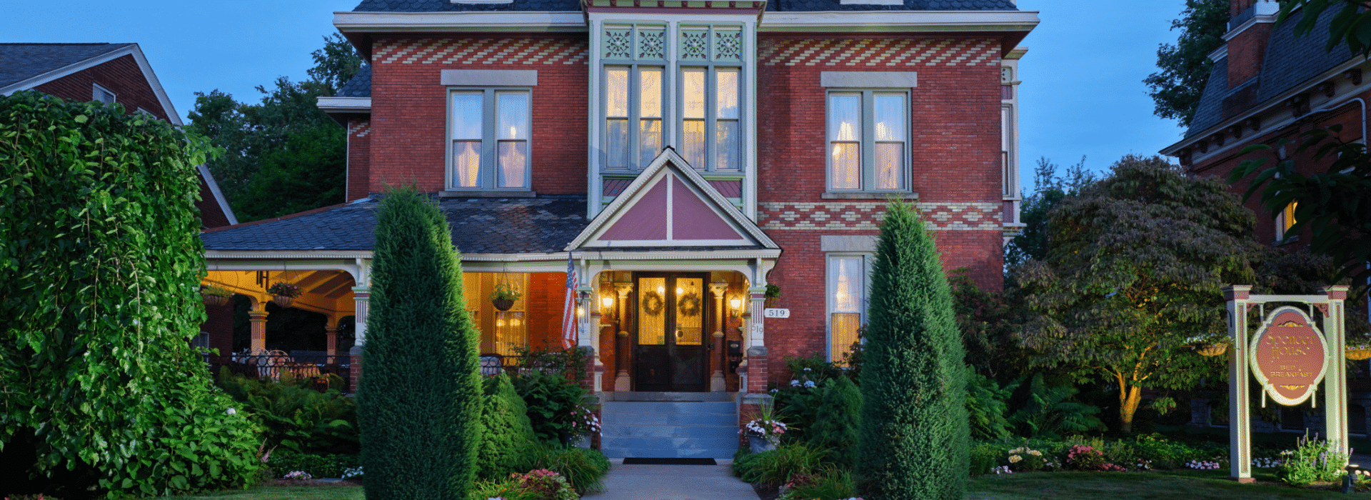 Spencer House Bed and Breakfast, a historic Victorian inn in Erie, Pennsylvania, warmly lit at dusk with welcoming front entrance and gardens.
