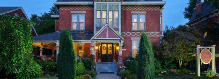 Spencer House Bed and Breakfast, a historic Victorian inn in Erie, Pennsylvania, warmly lit at dusk with welcoming front entrance and gardens.
