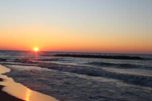 Picture of a Sunset over Lake Erie from a Presque Isle State Park beach with waves lapping up on the beack.