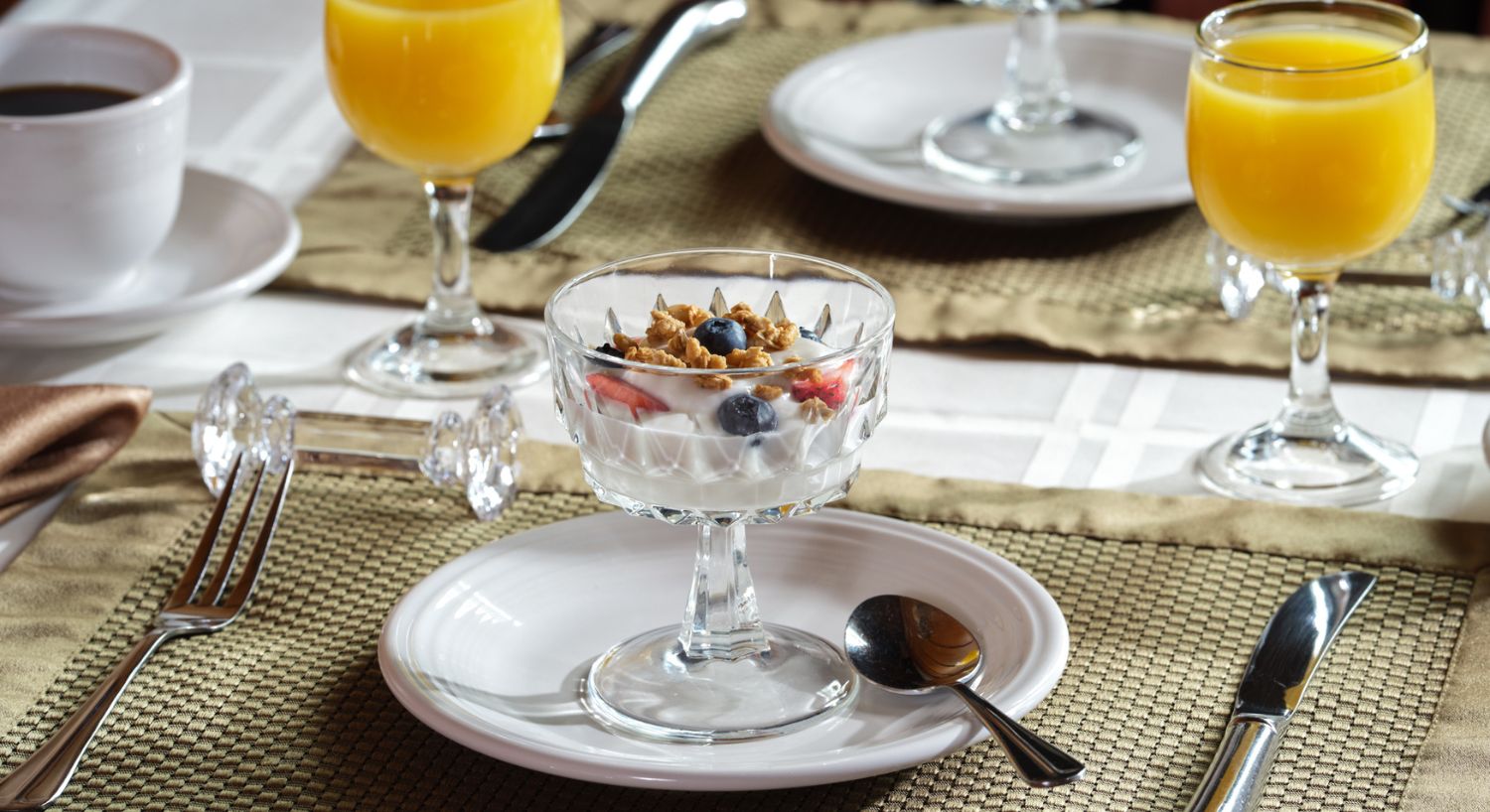 Yogurt parfait with fresh fruit and granola served with coffee and orange juice at Spencer House Bed and Breakfast in Erie, Pennsylvania.
