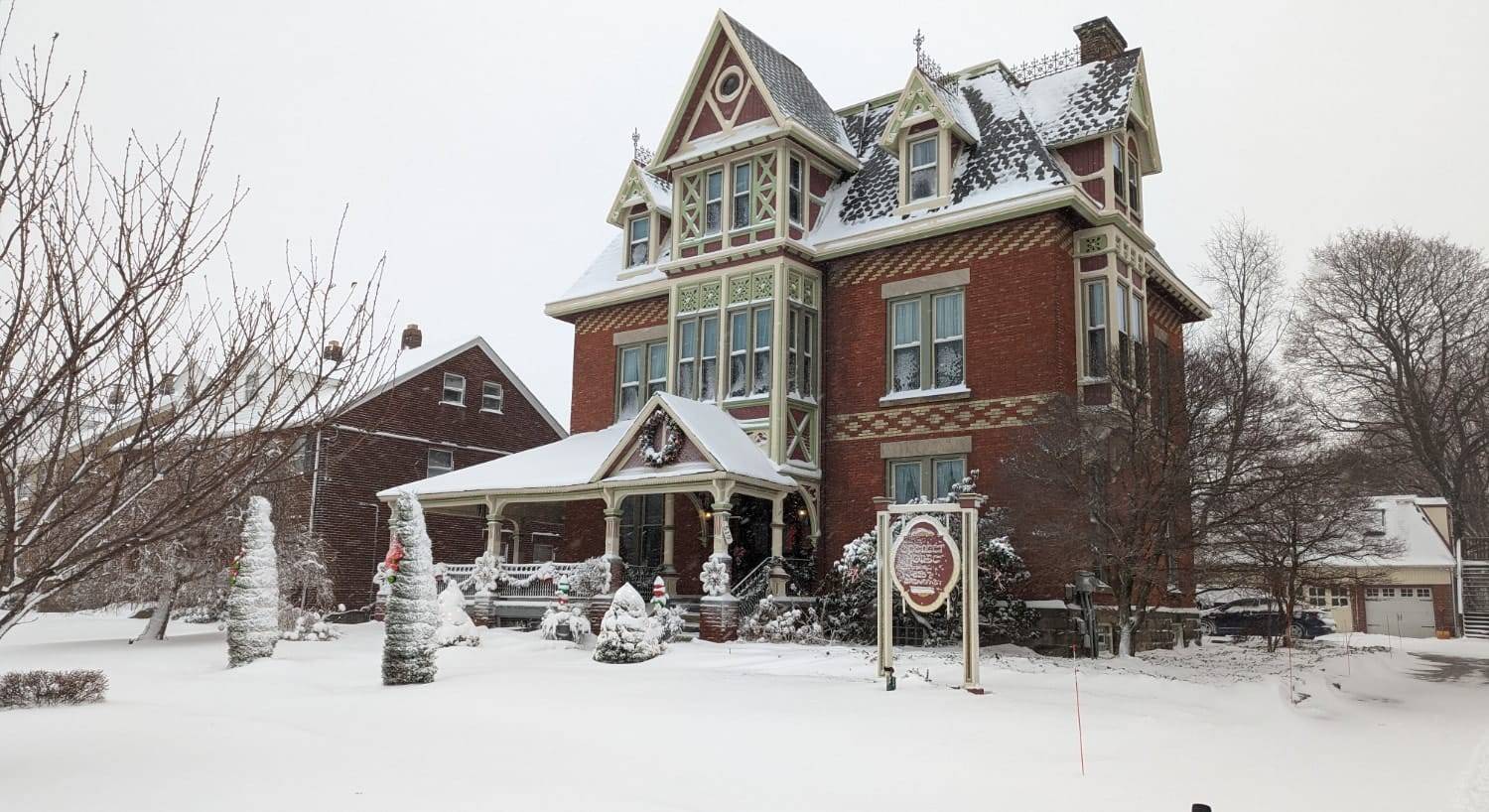 Exterior view of the property with red brick and white trim in the winter with snow all around